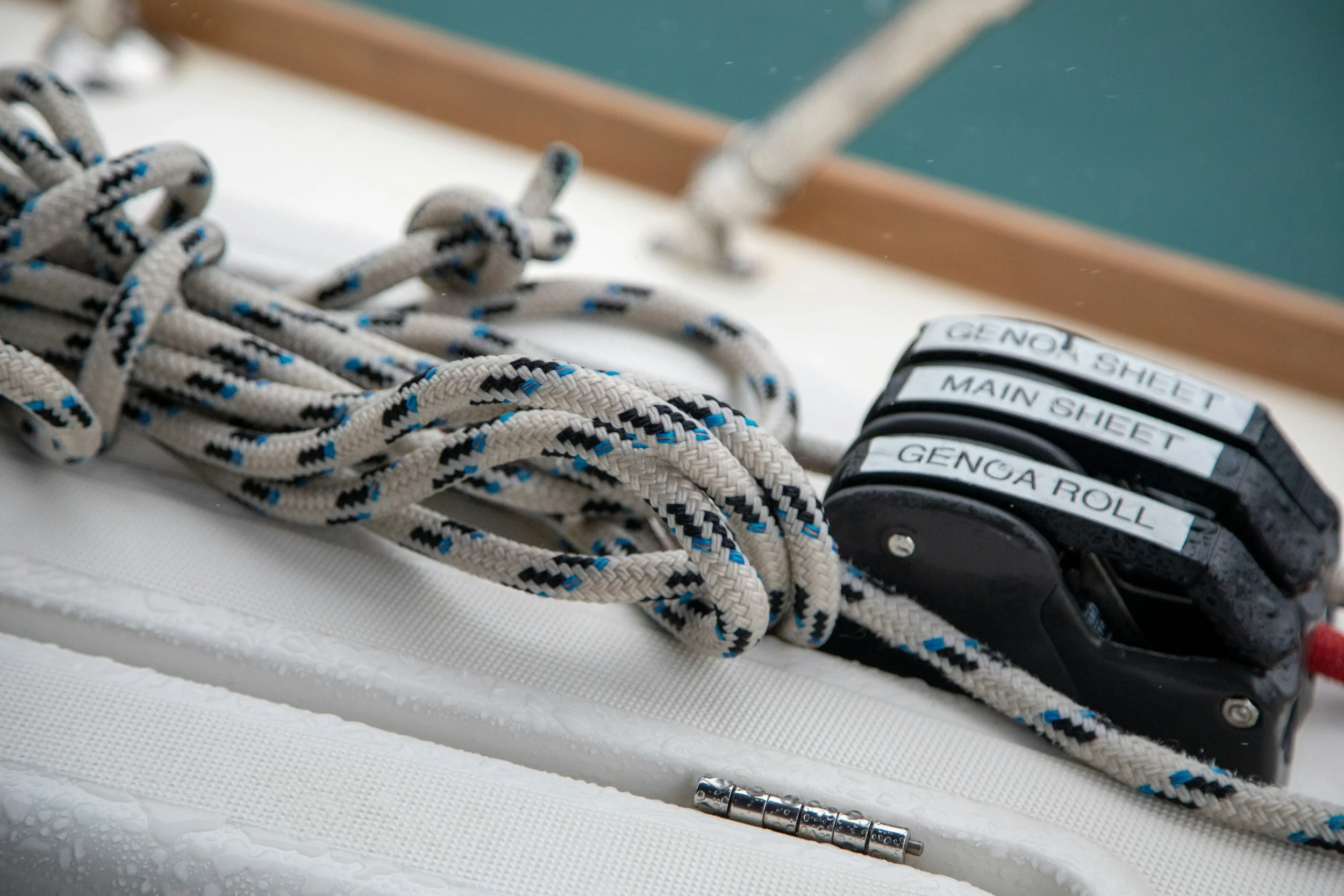 Close-up of a pair of ice skates with laces and a hockey puck on a textured white surface, with a teal wall and a wooden edge in the background.