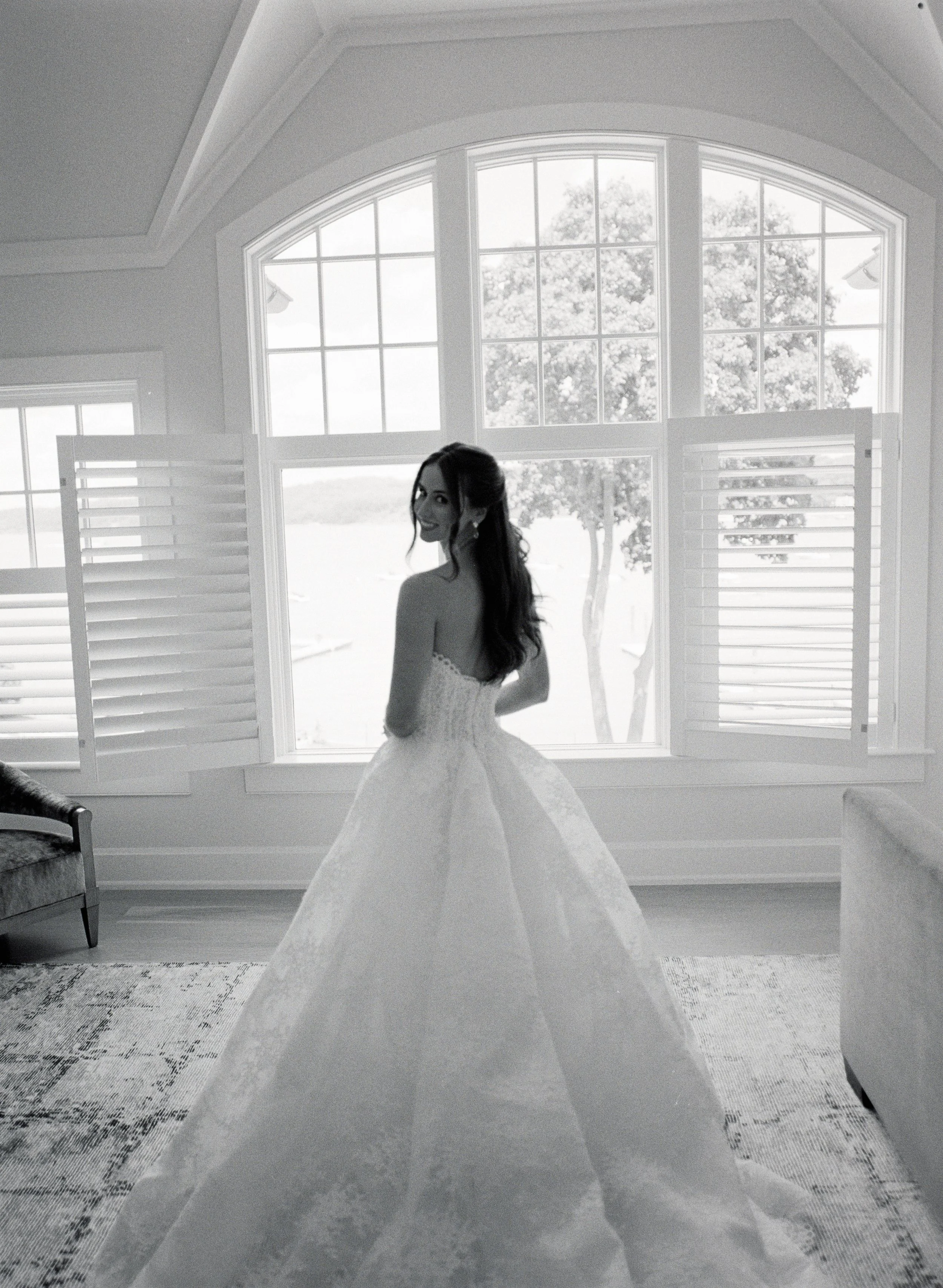 Black and White Photo of a Bride in Her Wedding Gown in Front of Window