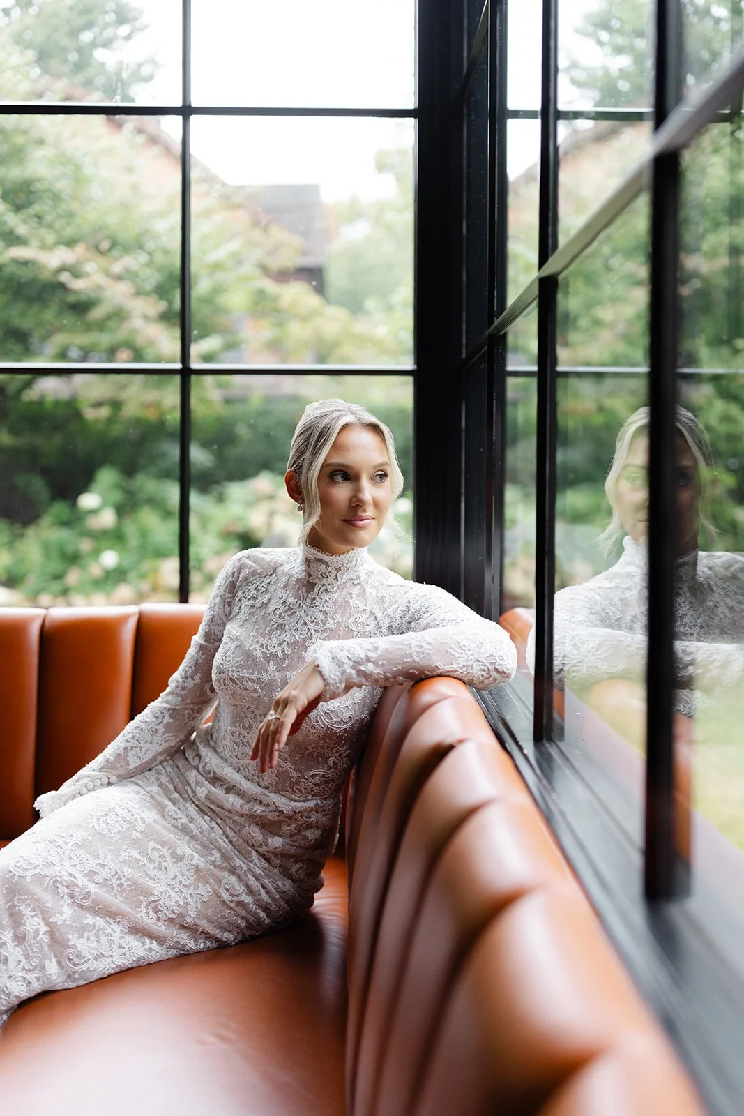 Bride in Wedding Dress Sitting on a Couch Looking Out a Window