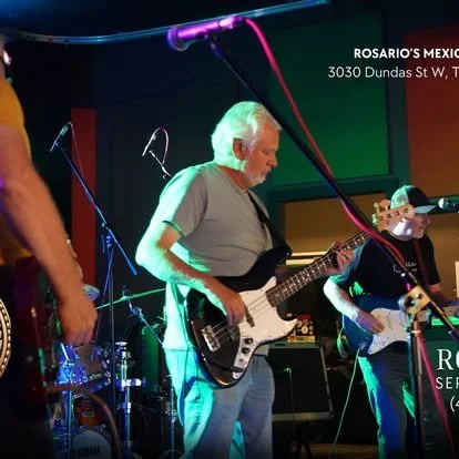 Two musicians playing electric guitars on stage during a live performance at Rosario's Mexican restaurant.