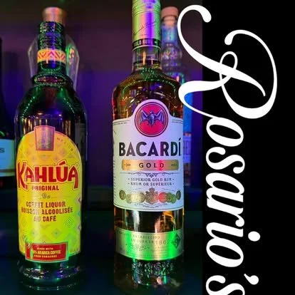 Two bottles of alcoholic beverages, one Kahúla Original and one Bacardi Gold, on a dark surface with a purple background, with the word 'Rosario:' written vertically on the right side.