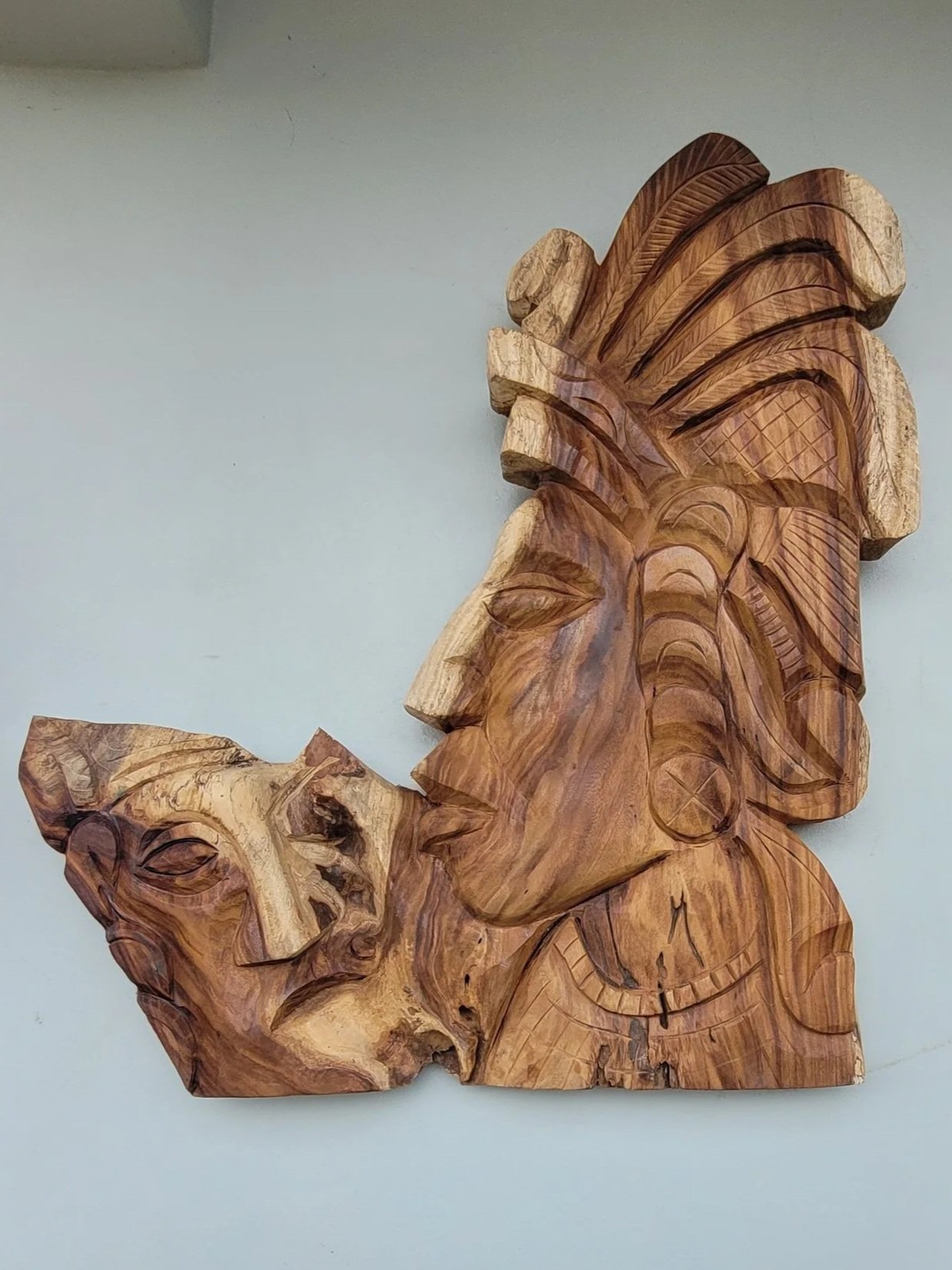 Wooden wall art sculpture depicting African tribal faces with intricate carvings and details.
