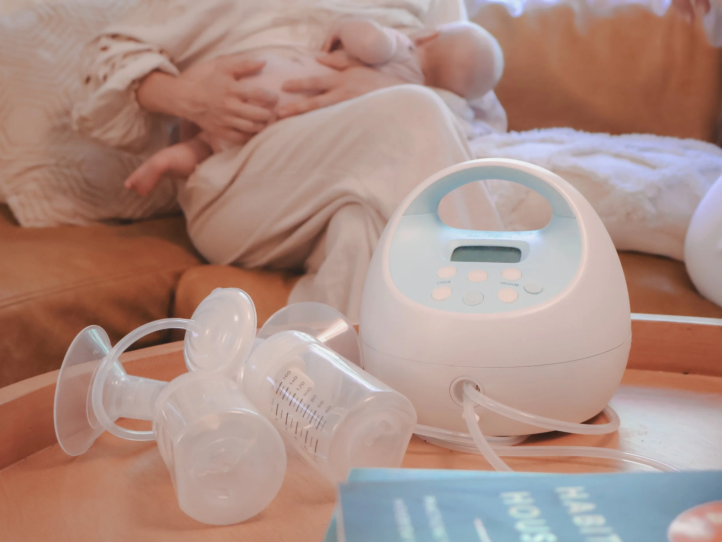 Close-up of a digital baby scale on a wooden surface with several clear plastic measuring cups scattered around.