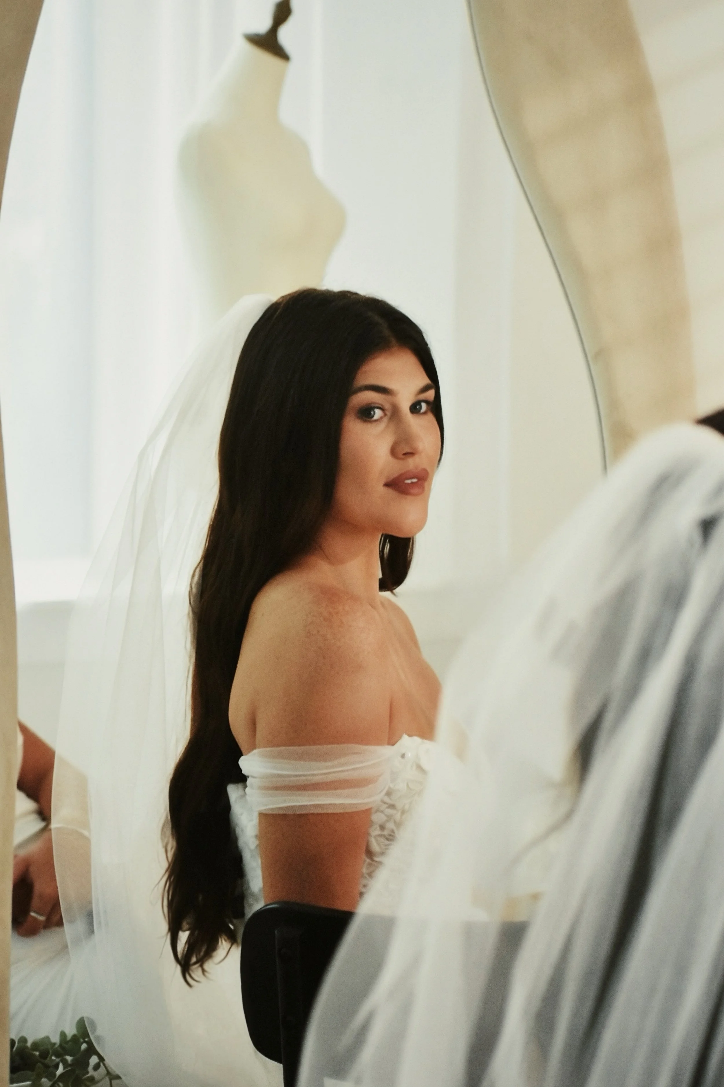 Modern wedding gowns at a size-inclusive bridal shop in Florida. Bride wearing a veil during a wedding dress appointment.