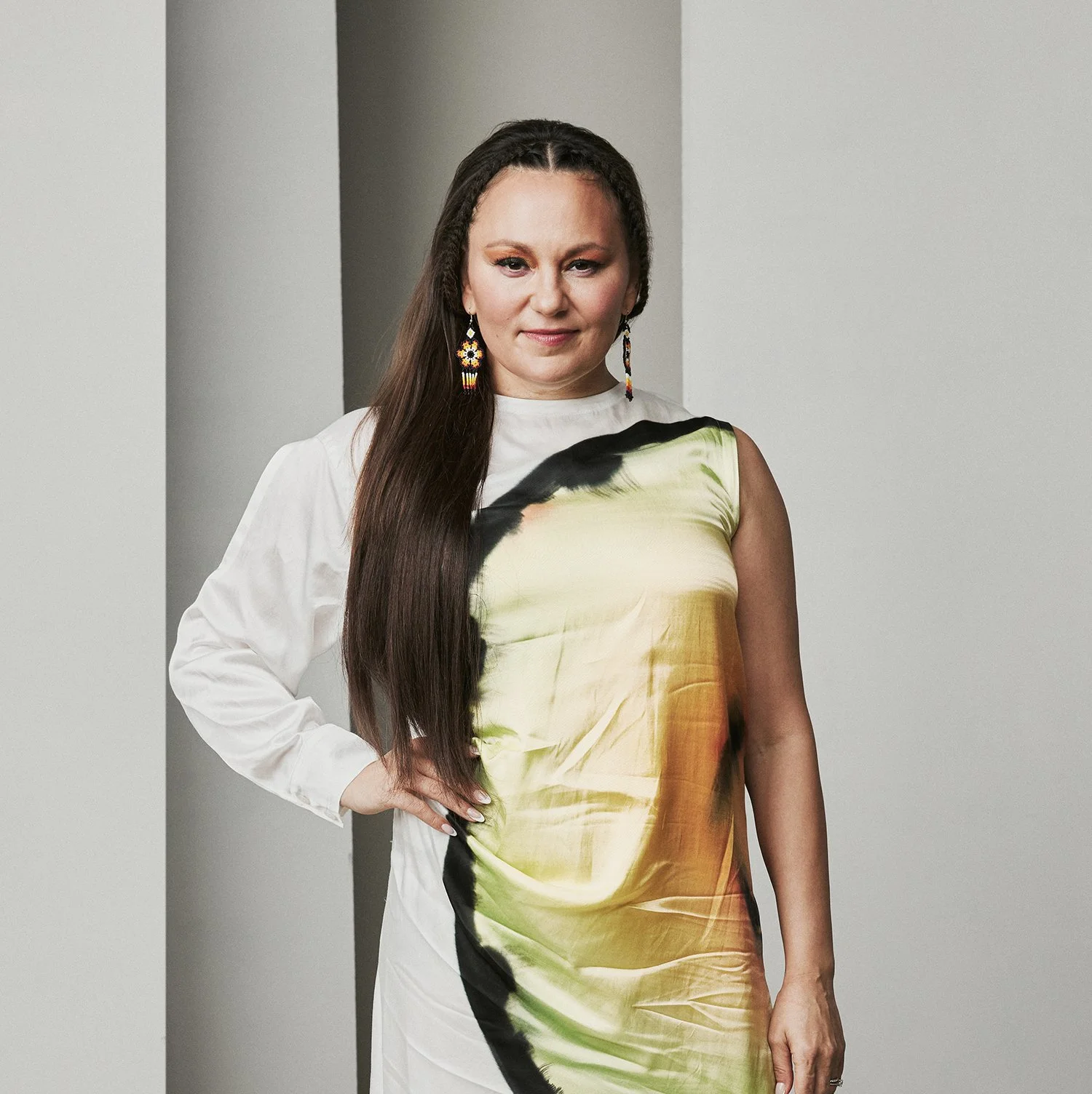 A press photo of Tanya Tagaq in a fashionable dress with a smile on her face..
