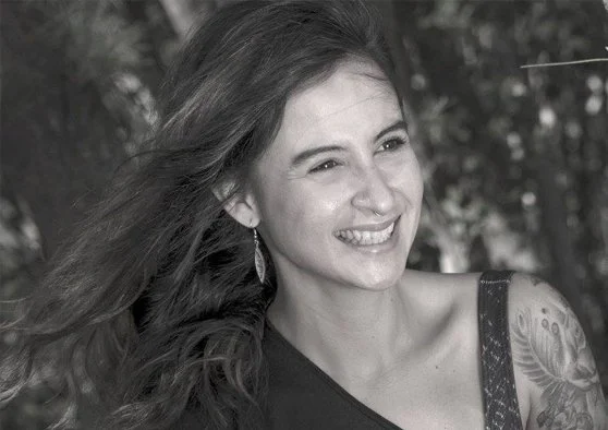 Black & white photo of Tina Wroblewski, smiling and looking away from the camera, hair flowing in the wind.