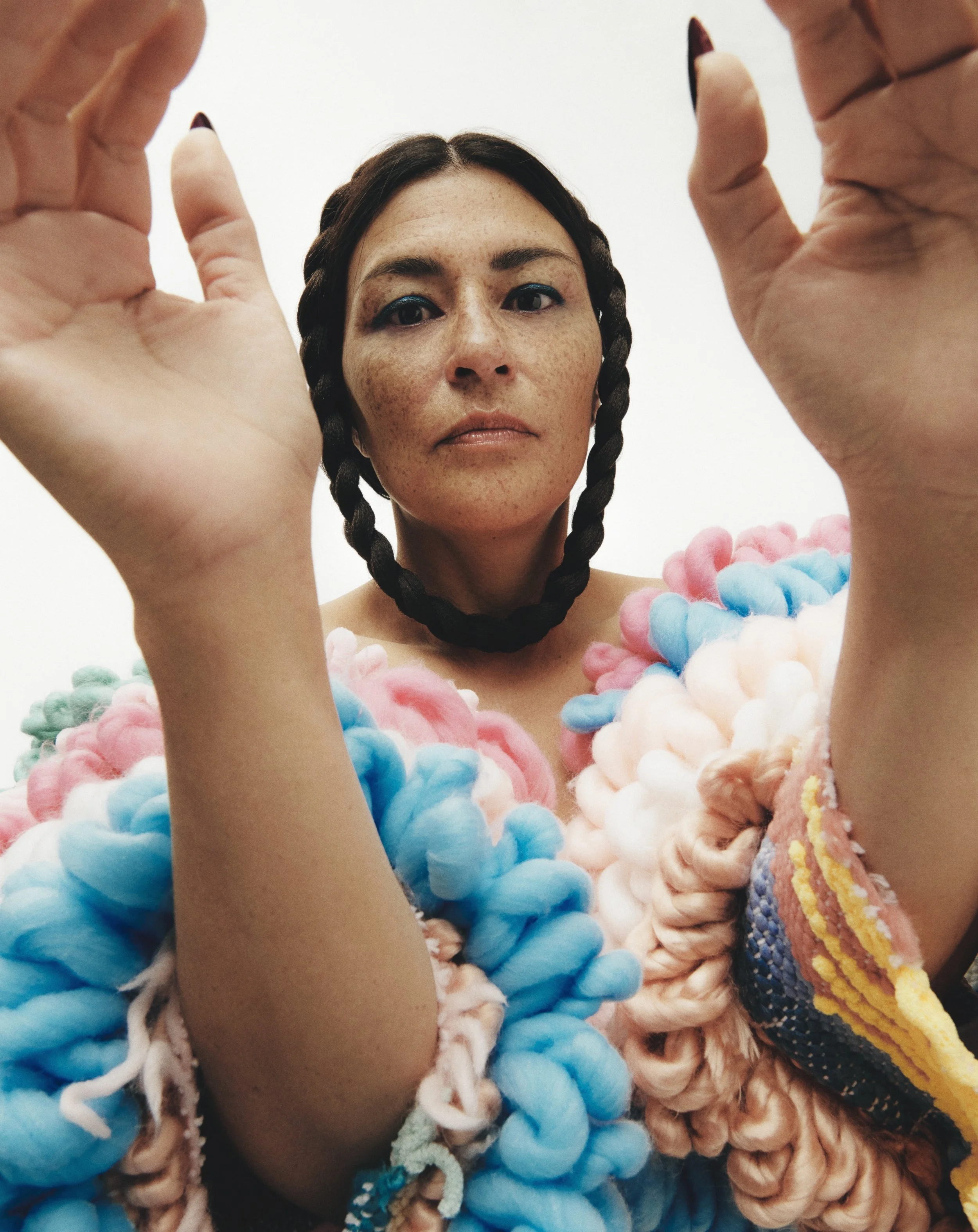 A close-up press photo of female Inuk artist Elisapie with puffy sleeves and braids that meet under her chin to make a complete loop.