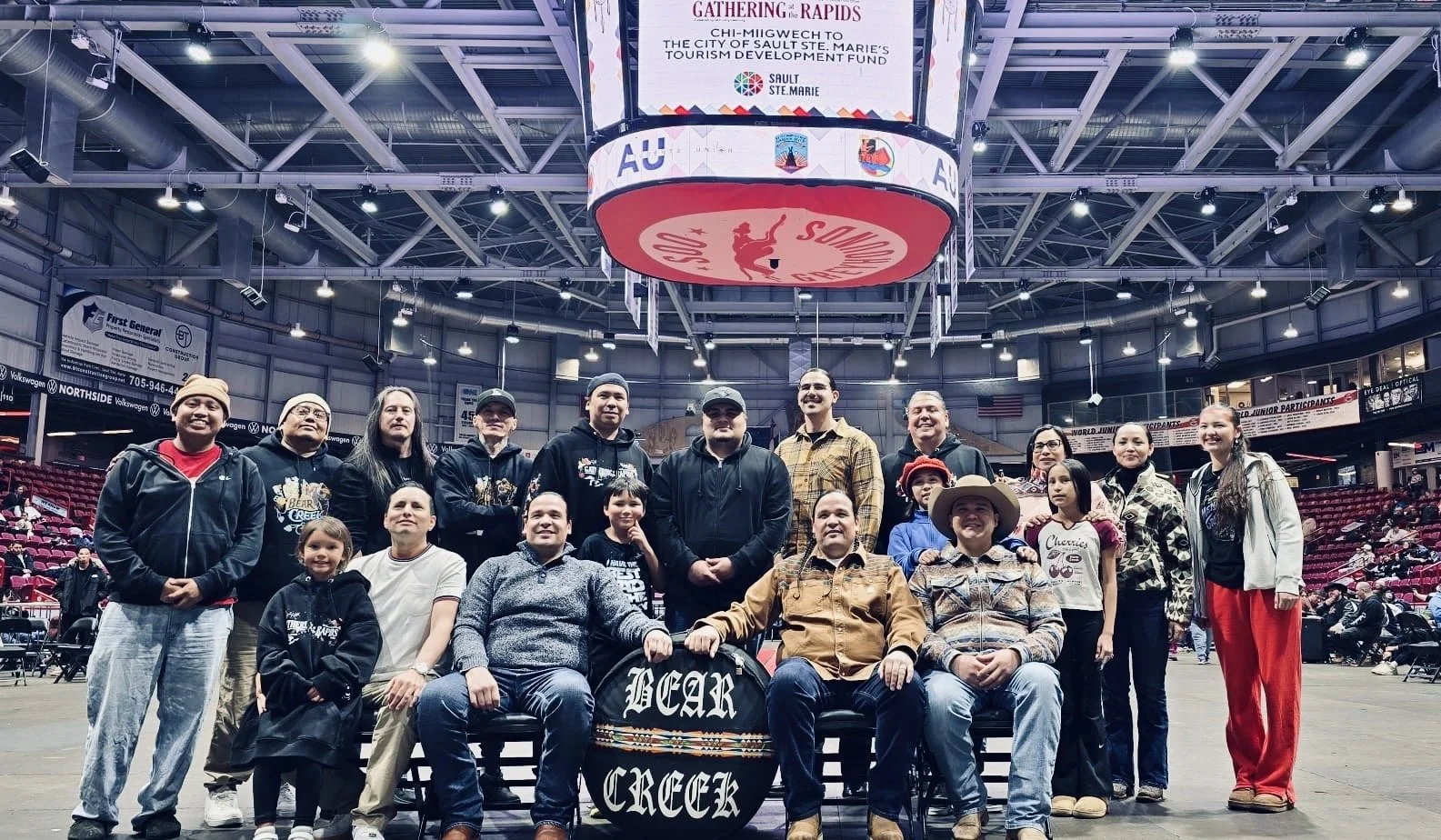 A photo of Bear Creek drum group posing for a photo in a hockey arena.