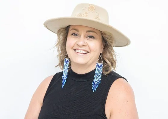 Photo of Elizabeth Bunney wearking a deadly fedora and big beaded earrings.