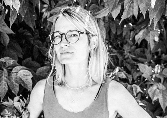 A black and white photo of Emily Smart wearing glasses and a tank top.