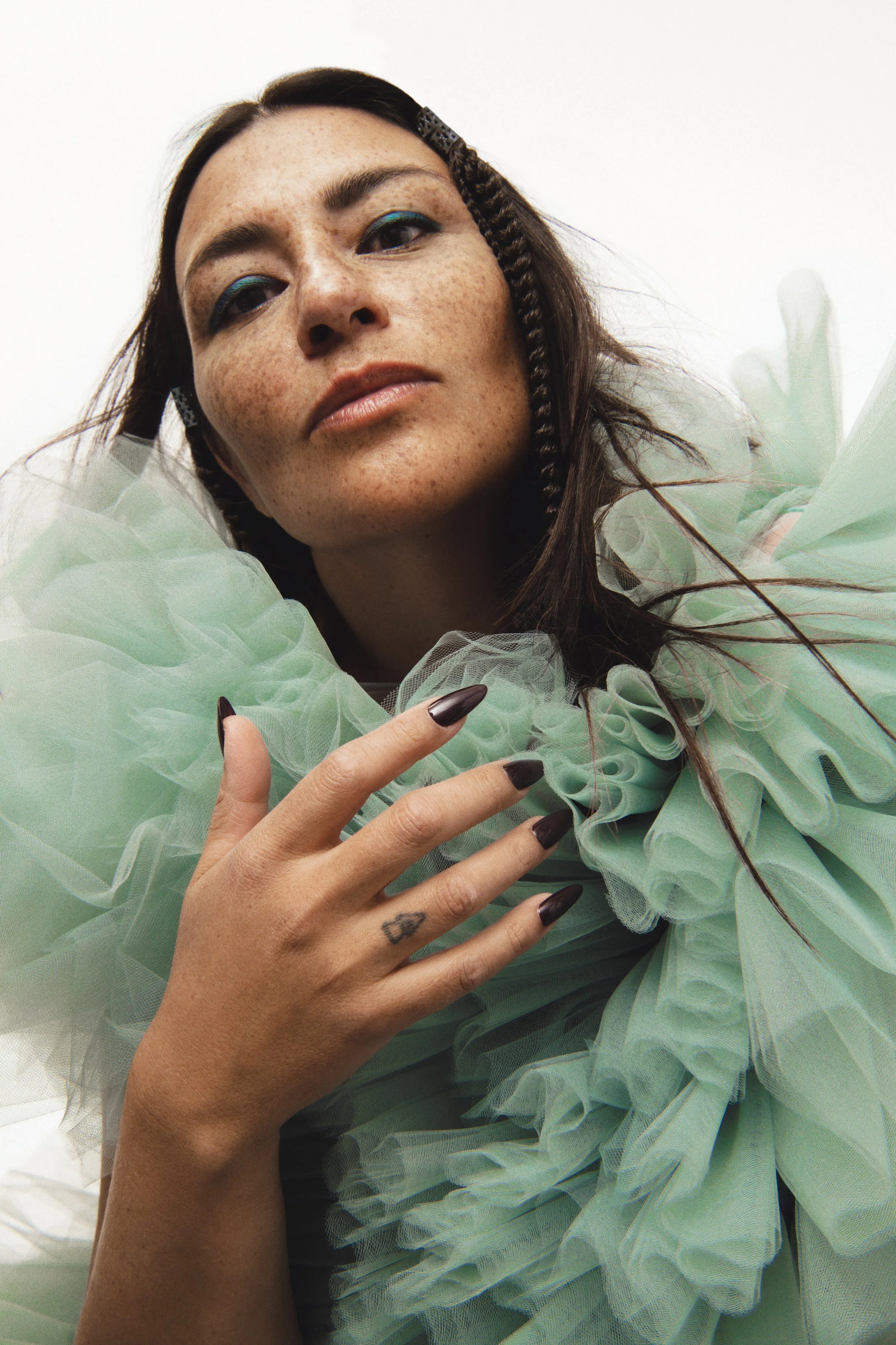 A press photo of Elisapie wearing a frilly torquoise scarf.