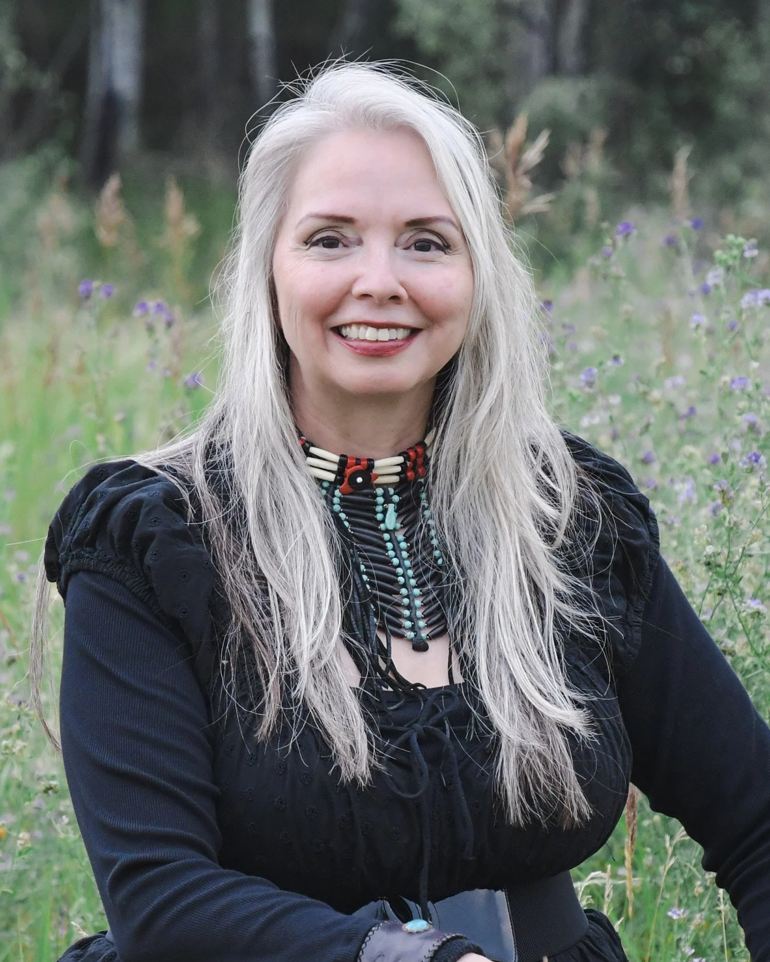 Photo of Veronica Johnny in a field wearing a bone choker/breastplate.