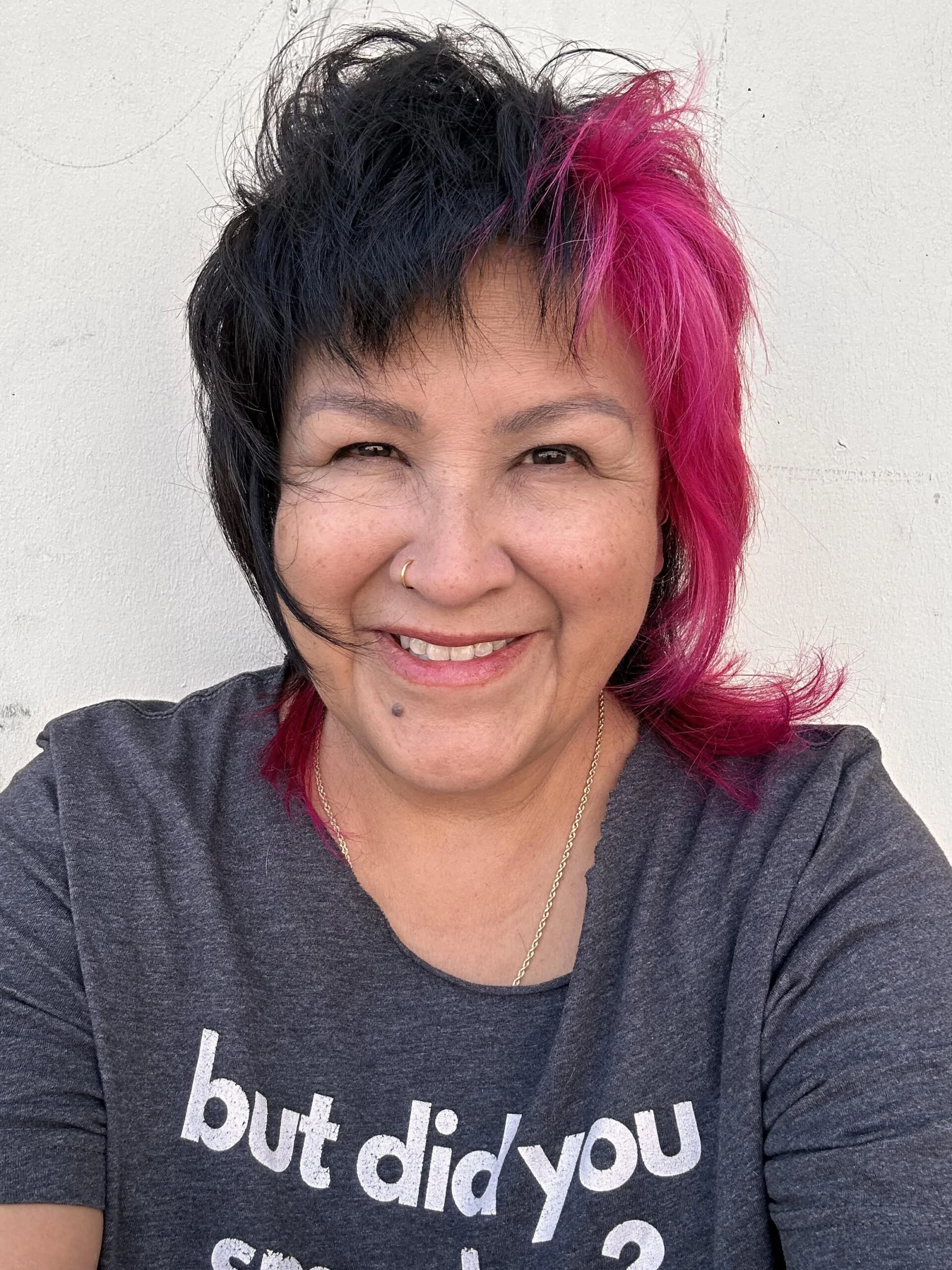 A selfie of Kim Wheeler smiling, wearing a t-shirt with her hair split black and reddish pink like a cool auntie!