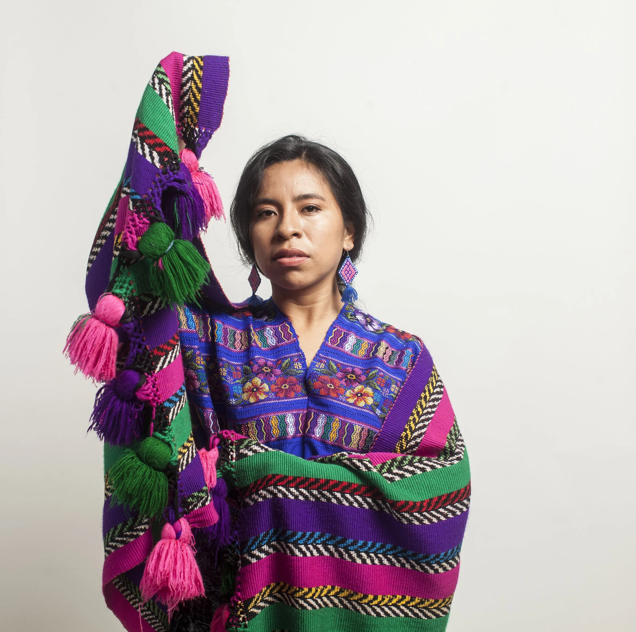 A press photo of Sara Curruchich wearing a traditional Indigenous outfit and looking serious at the camera..