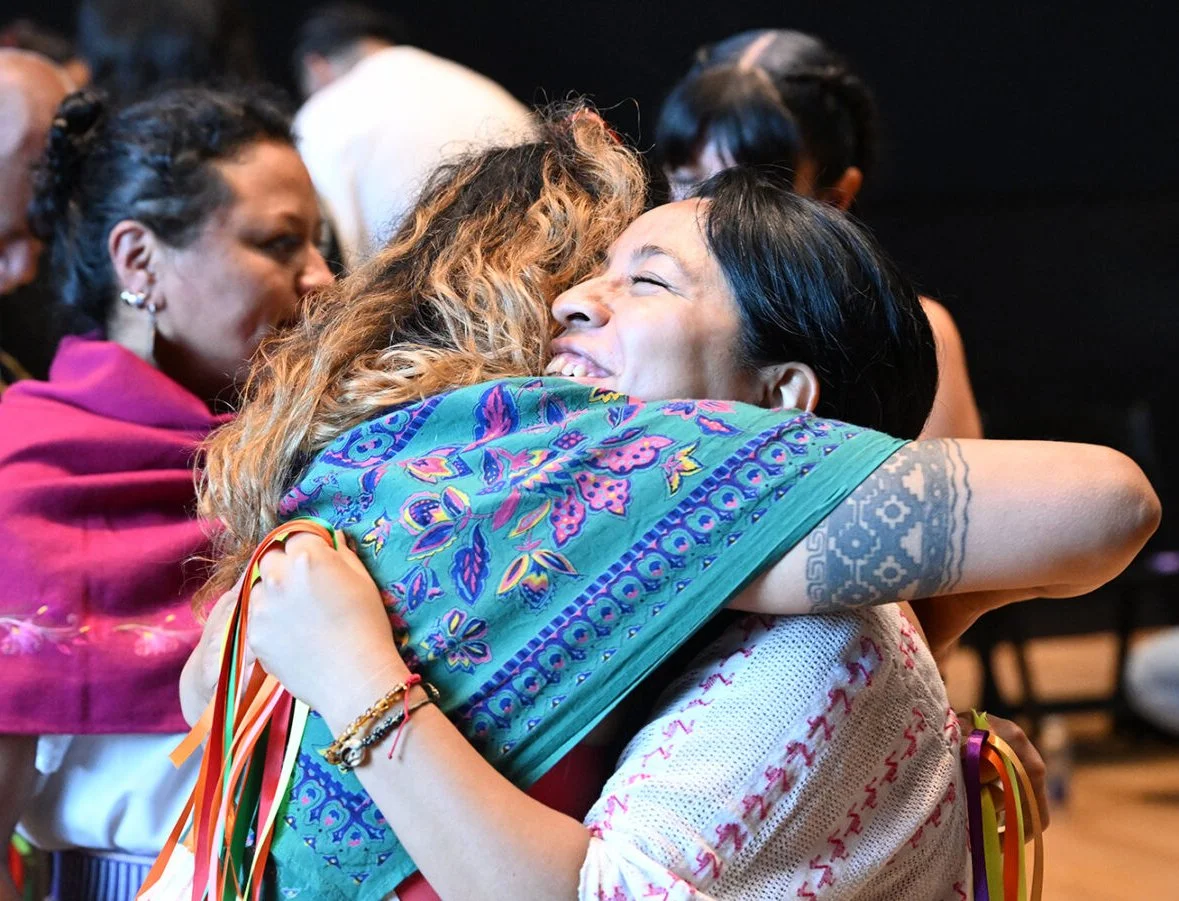 A photo of two IIMS attendees embraced in a hug.