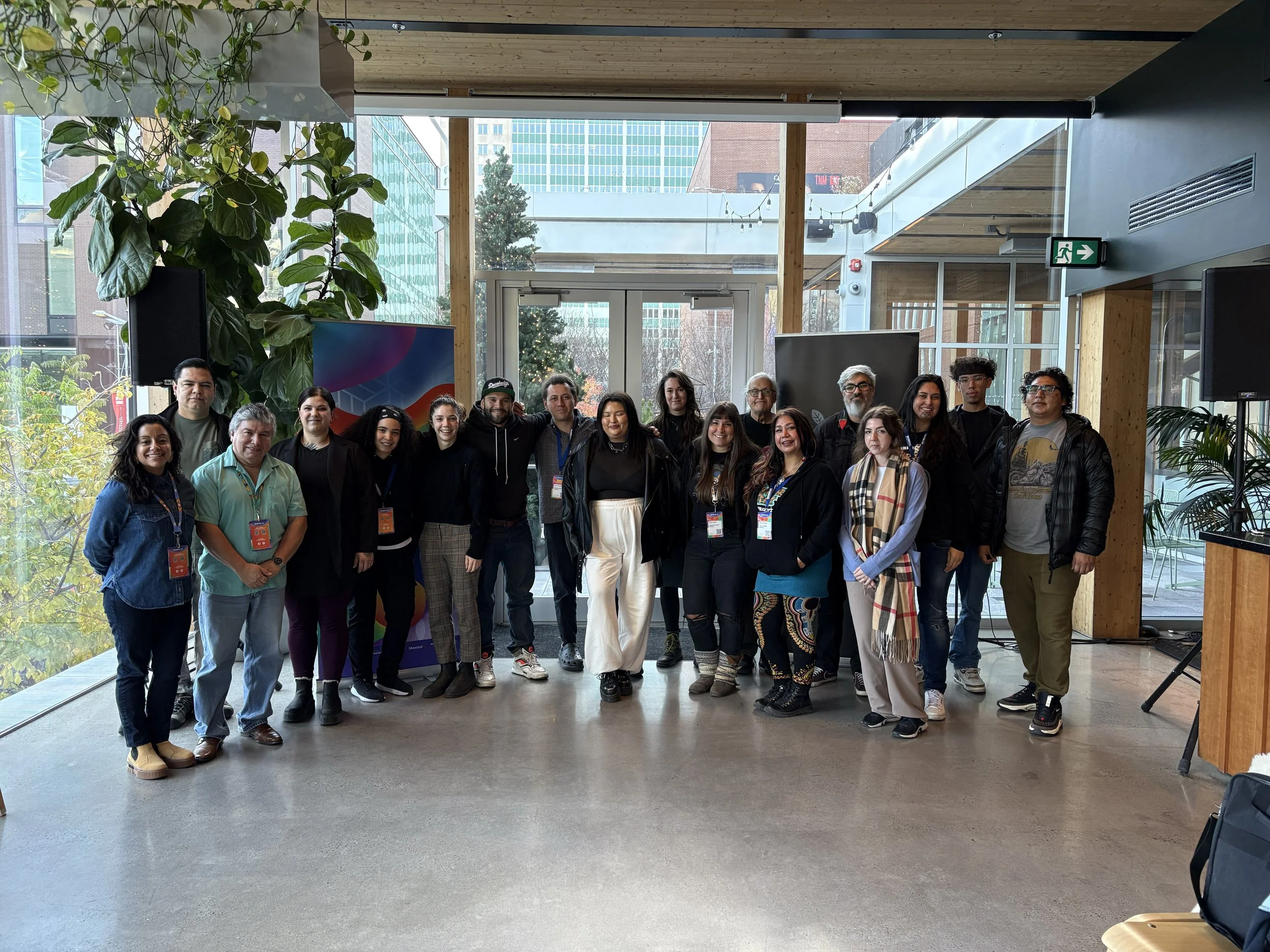 A group photo of approximately 20 people standing in a meeting room in a foyer, smiling at the camera.