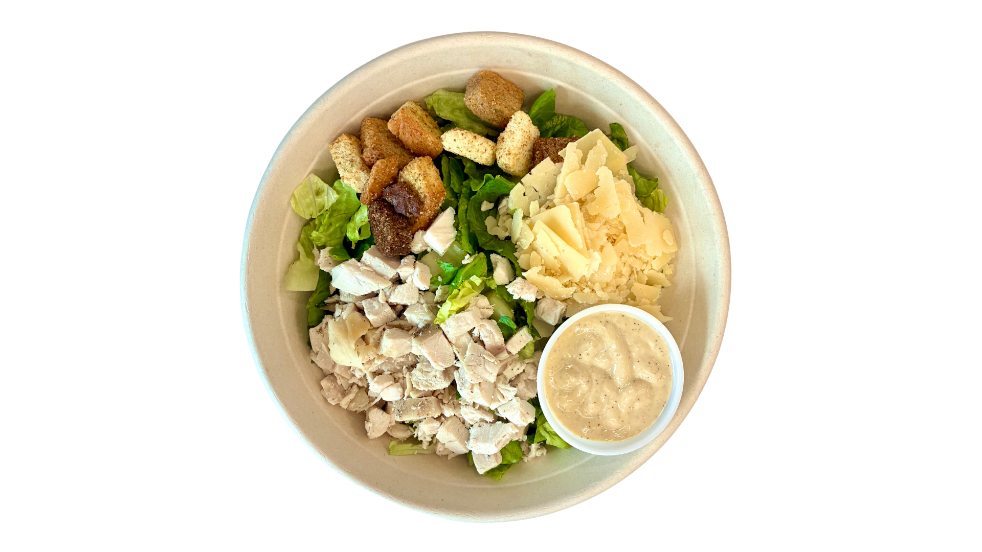 Salad in a bowl with chopped chicken, shredded cheese, croutons, sliced chicken, and a side of creamy dressing.