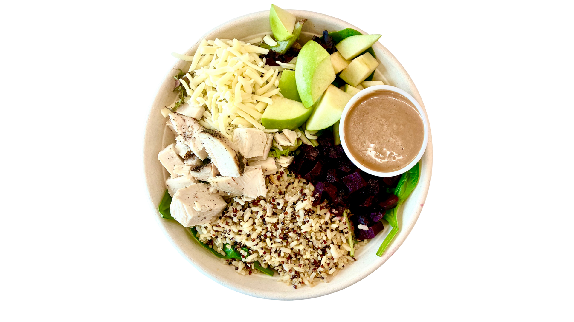 A Buddha bowl with chopped grilled chicken, shredded cheese, diced avocado, chopped beets, cooked quinoa, and a side of dressing in a small container.