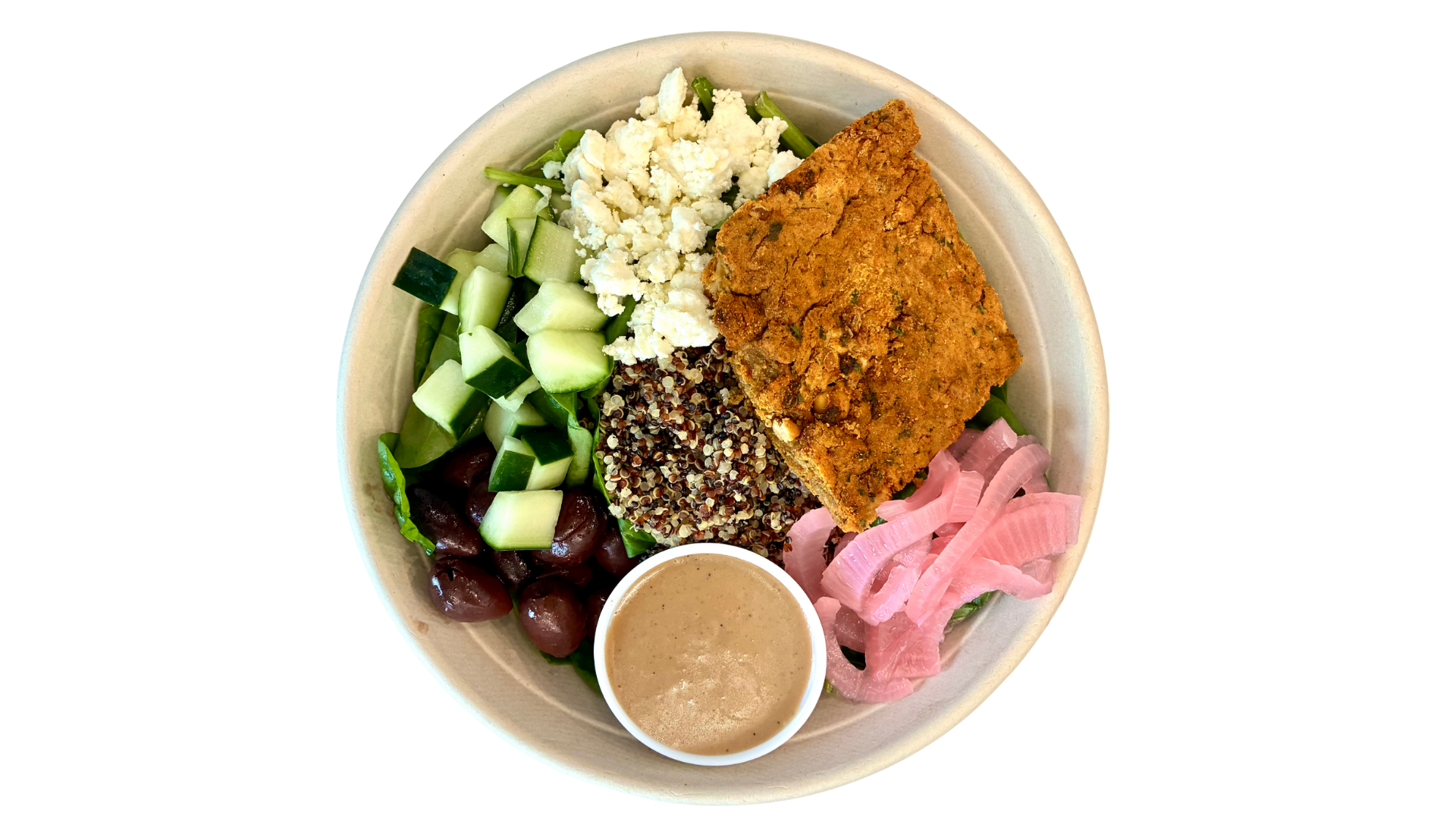 A Mediterranean salad bowl with cucumbers, cherries, crumbled cheese, quinoa, fried fish fillet, pink pickled onions, and a small container of dressing