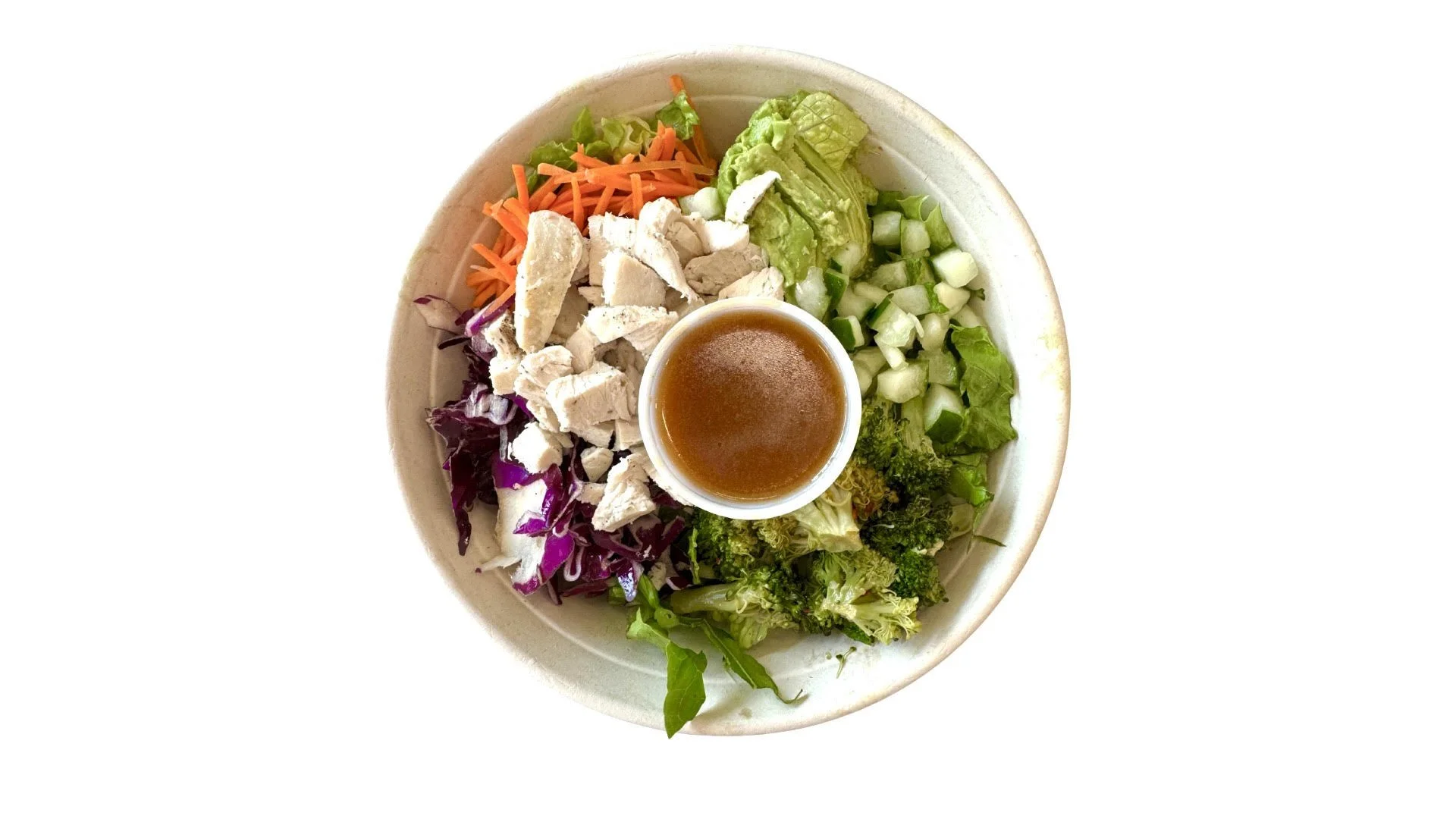 Mixed greens and chopped vegetables salad with shredded carrots, chopped cucumbers, lettuce, purple cabbage, and chopped chicken, served with a small cup of vinaigrette dressing.