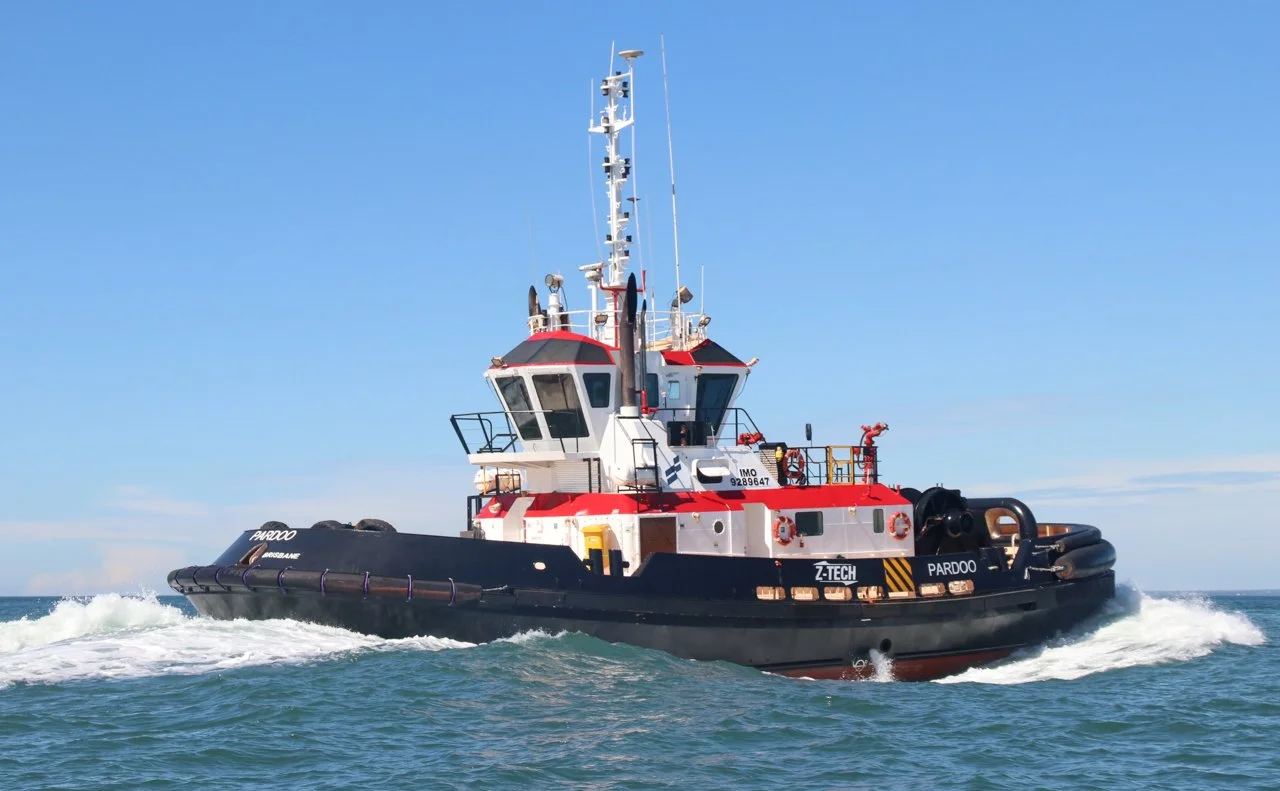 A tugboat sailing on the ocean with a clear blue sky in the background.