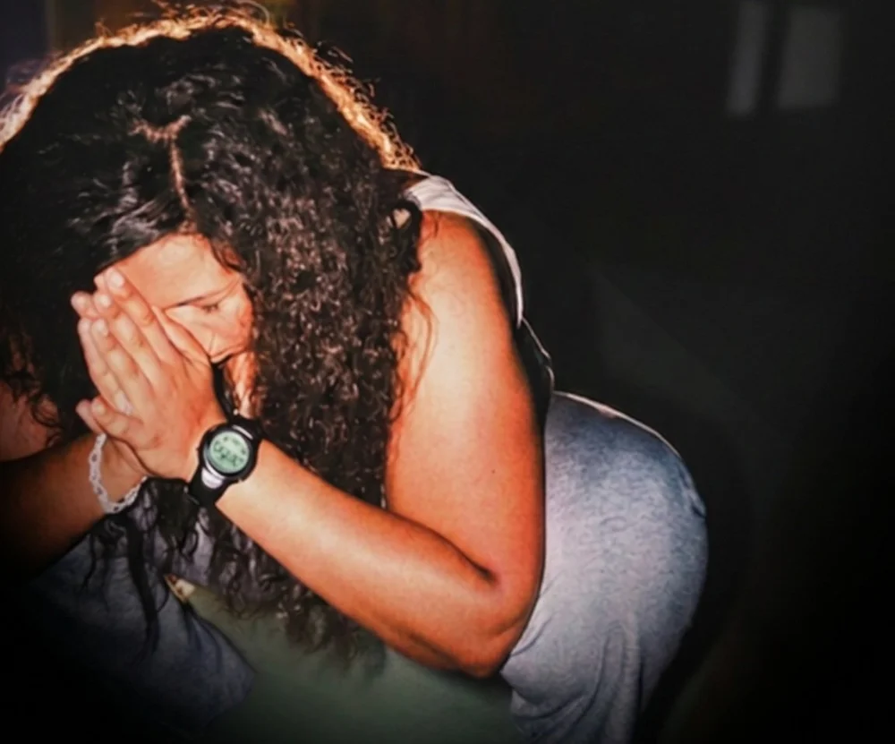 A woman bowed low with her hands over her face