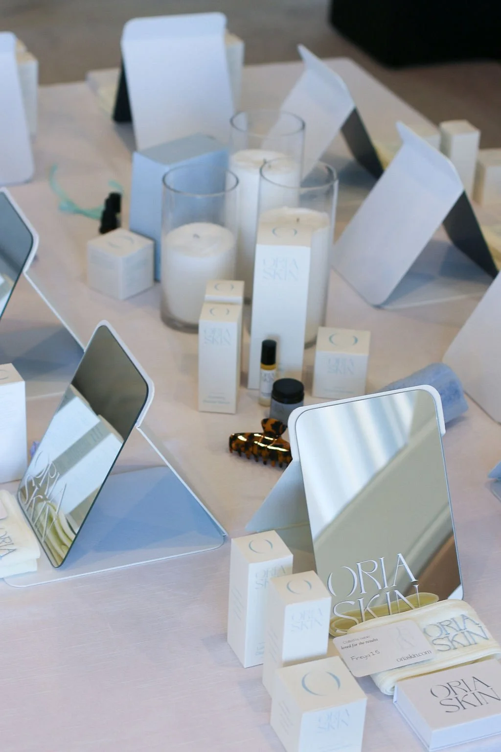 Table with beauty stations including small mirror, Oria Skin products with white candles, white and soft blue colouring