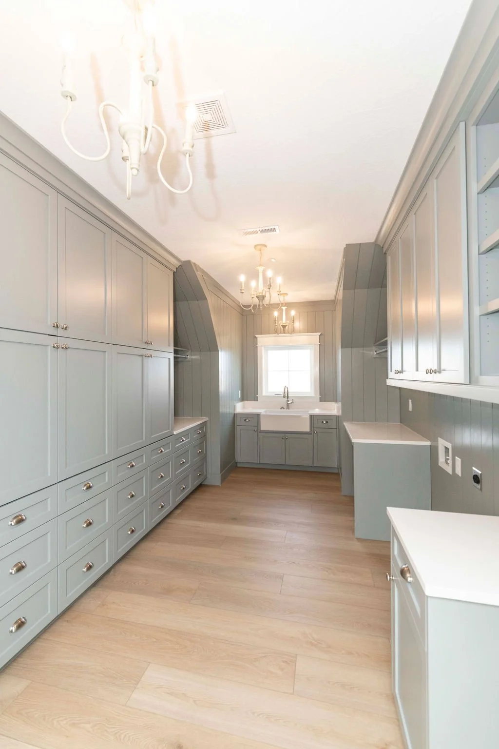 Empty laundry or utility room with built-in cabinets, a white farmhouse sink, and light-colored wood flooring.