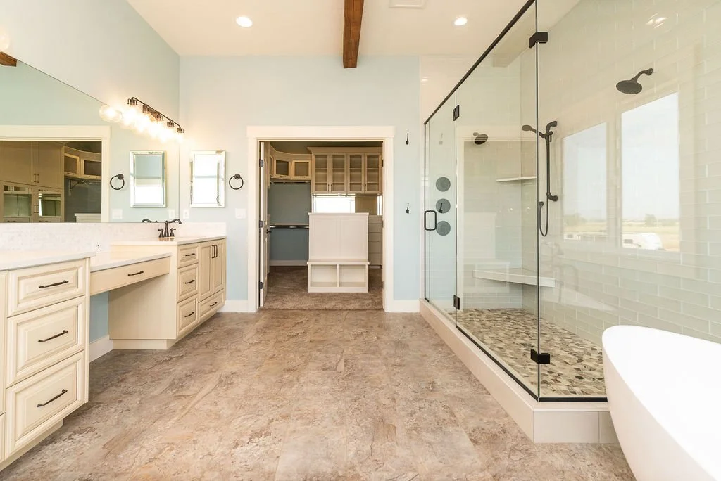 Modern bathroom with dual vanity sinks, large mirror, and a spacious glass-enclosed shower with multiple showerheads.