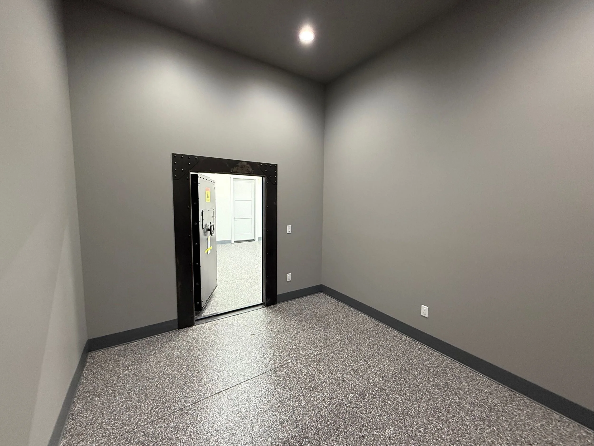 Interior of a room with gray walls and a vending machine visible through a doorway.