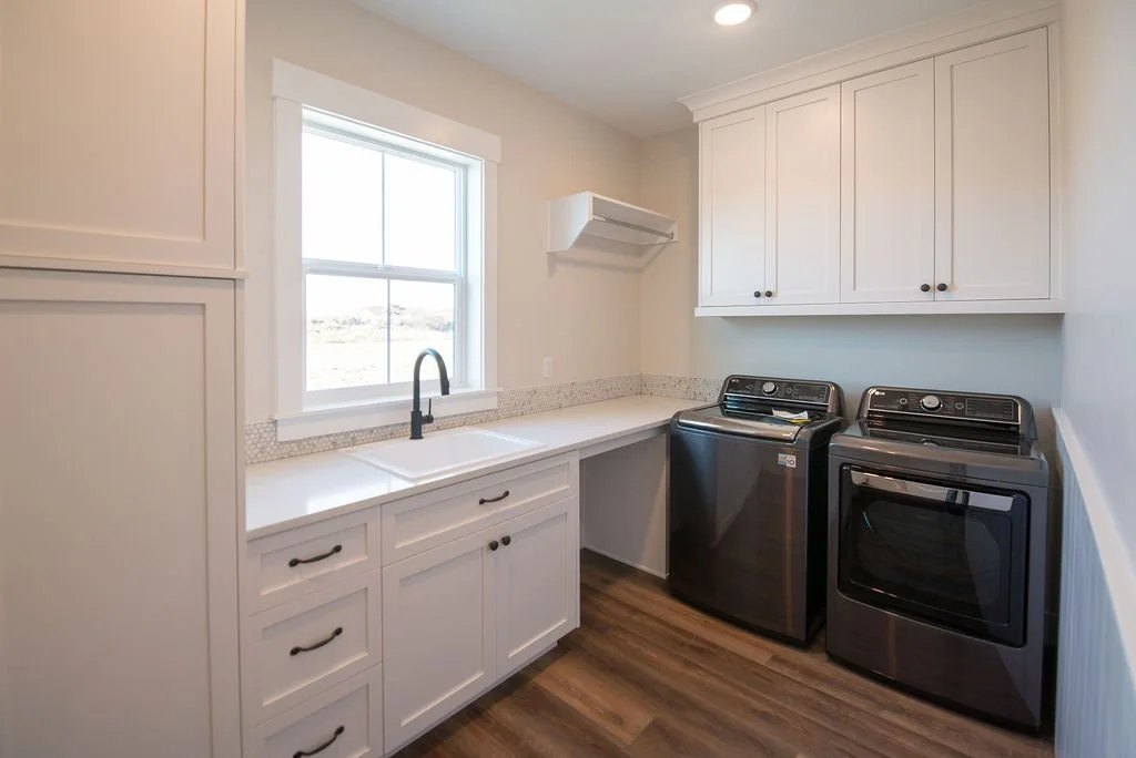 Laundry room with white cabinets, a window, a double sink, and a washer and dryer.