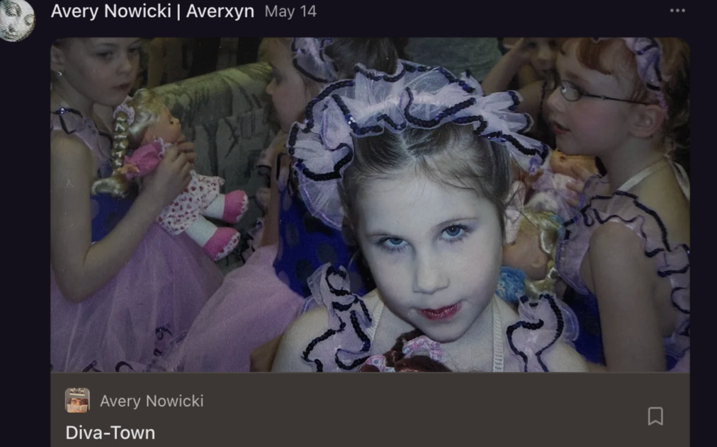 Young girls dressed in colorful fairy or princess costumes with frilly headbands and bright makeup, gathered closely together at an indoor event.
