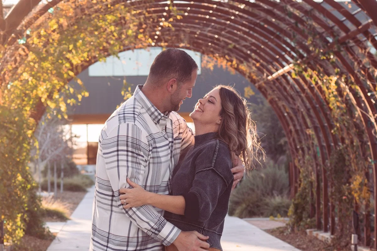 Couple standing under archway smiling at eachother