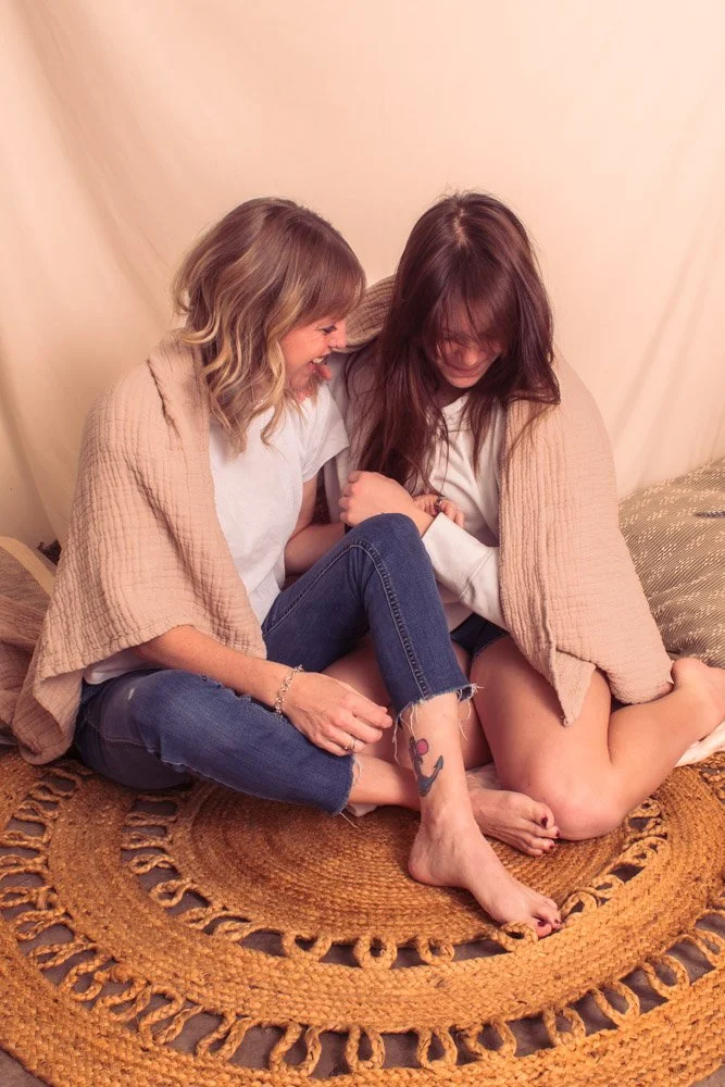 mother and daughter sitting on floor laughing together