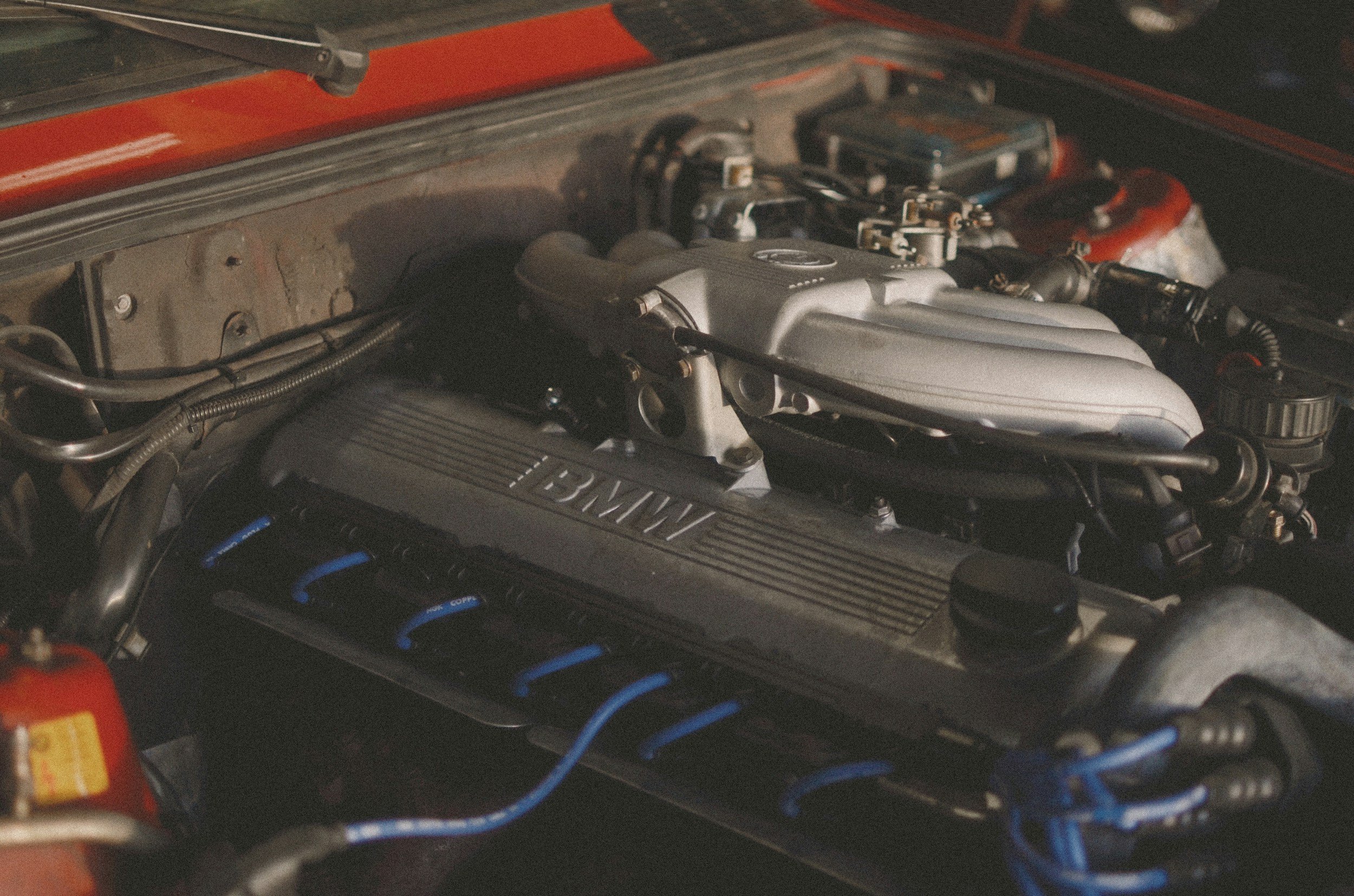 A close-up view of a car engine with various components including intake manifold, wiring, and engine block, surrounded by a red frame.