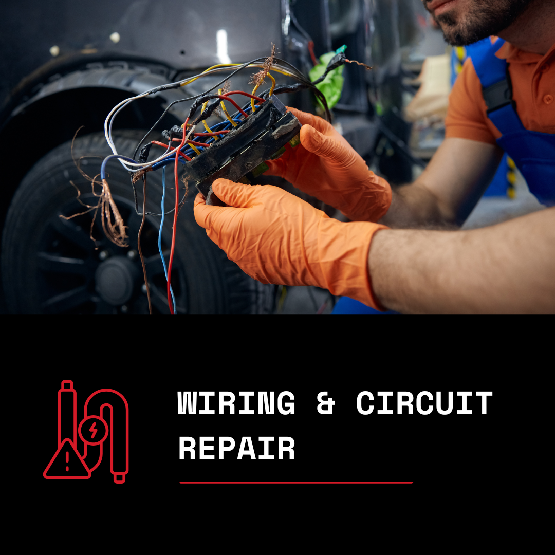 A mechanic wearing orange gloves working on exposed car wiring and circuitry.