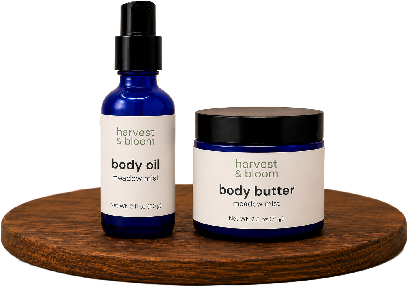 Shop the Harvest and Bloom body skincare set pairing a full-size botanical body oil and whipped tallow body butter on a wooden riser.