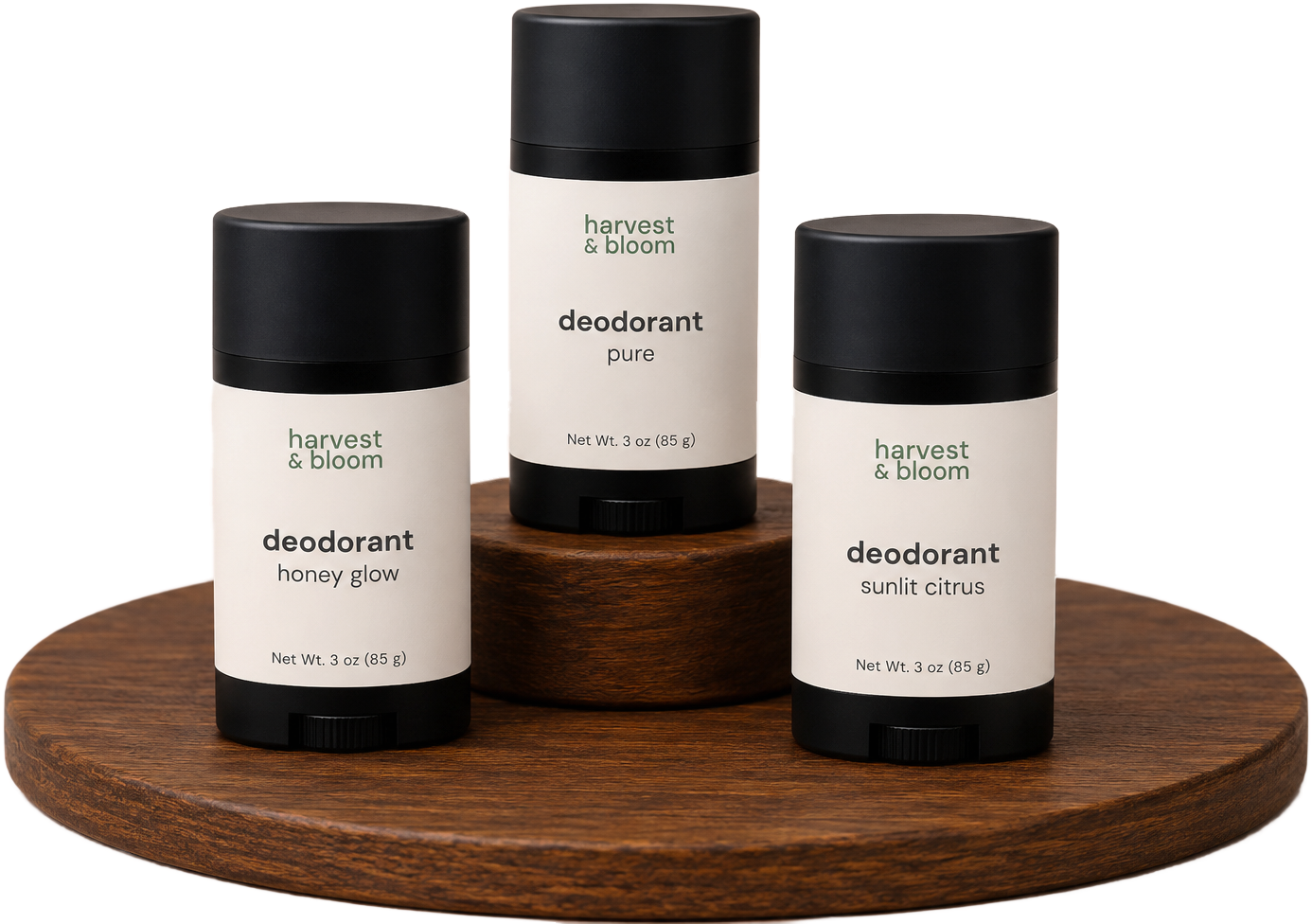 Three matte black twist-up sticks of Harvest & Bloom botanical deodorant displayed on tiered wooden risers, available in Pure unscented, Honey Glow, and Sunlit Citrus scents.