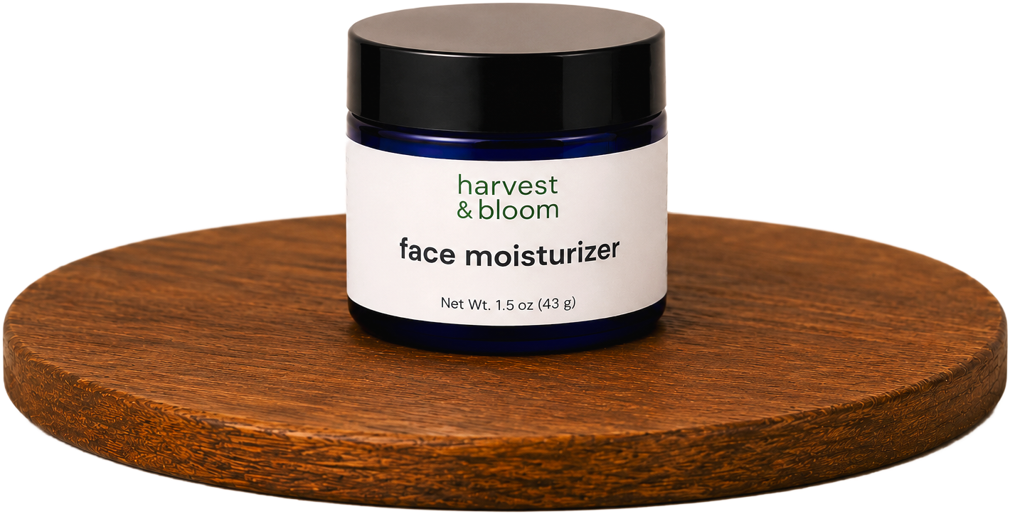 A cobalt blue glass jar of Harvest & Bloom waterless face moisturizer on a round wooden tray, highlighting the clean brand typography.