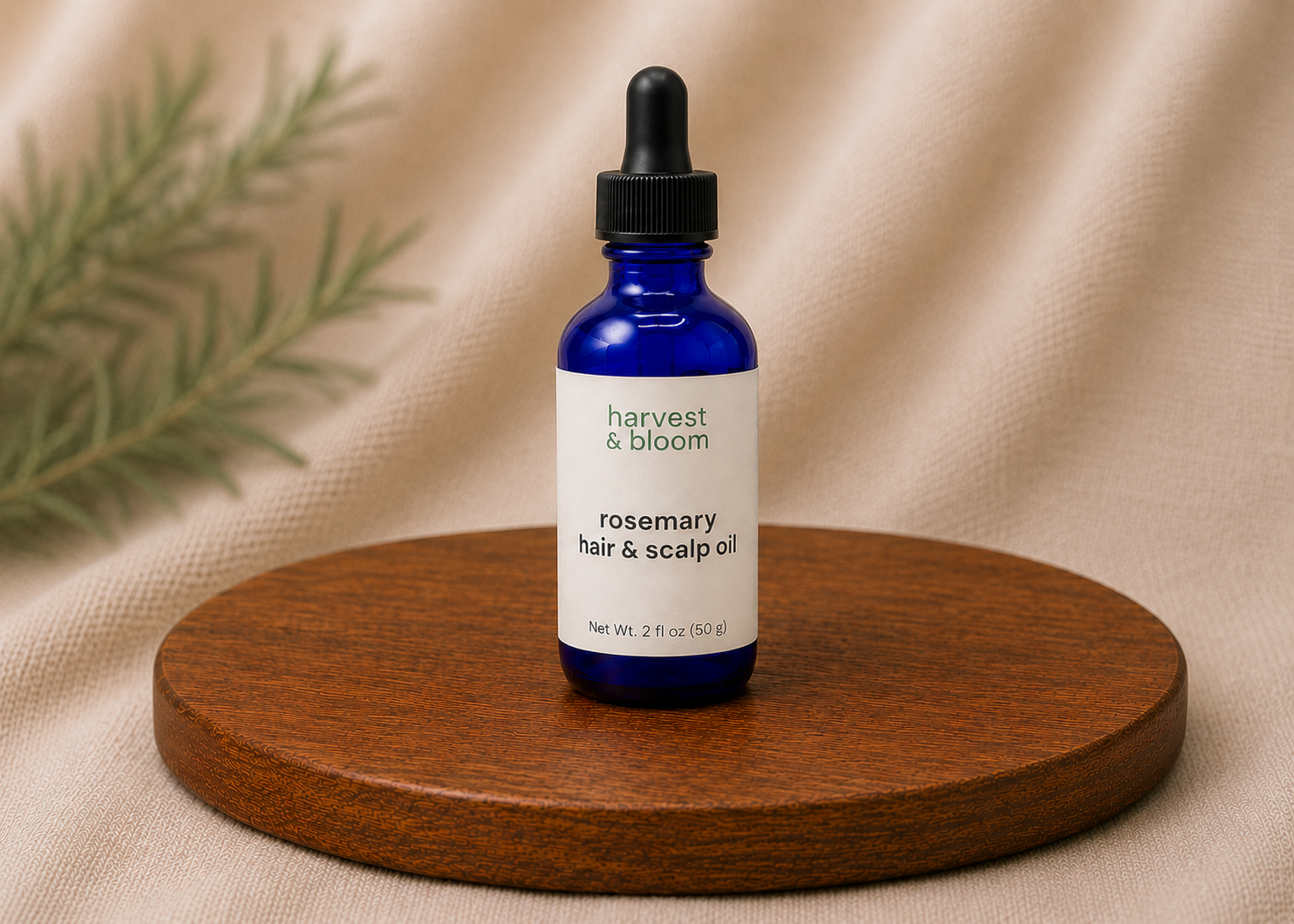 Harvest and Bloom natural rosemary hair and scalp oil in a blue glass bottle with a premium dropper assembly against a soft backdrop.
