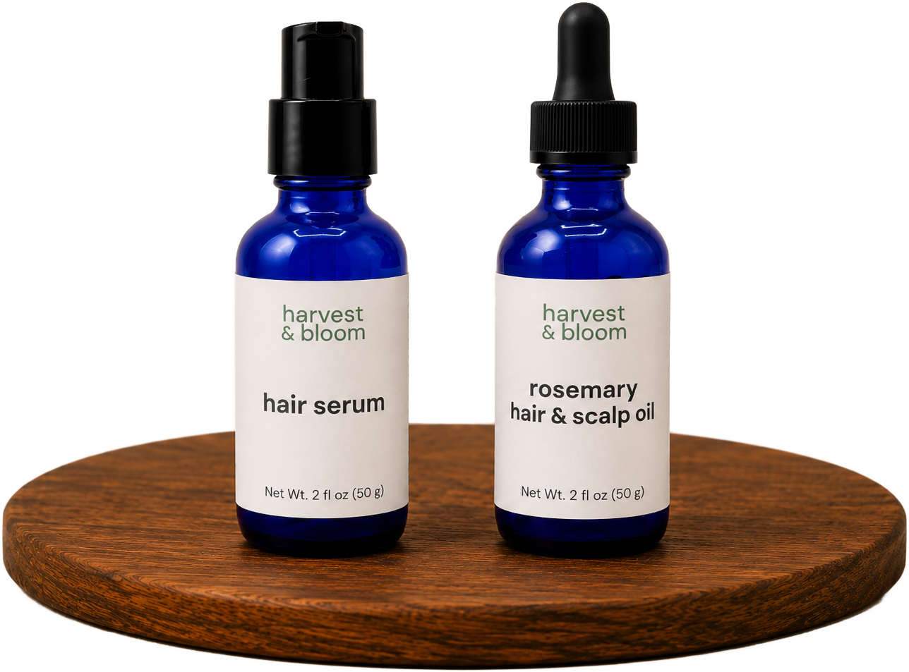 A Harvest & Bloom Haircare Set featuring a cobalt blue glass pump bottle of hair serum and a matching dropper bottle of rosemary hair oil side-by-side on a round wooden tray.