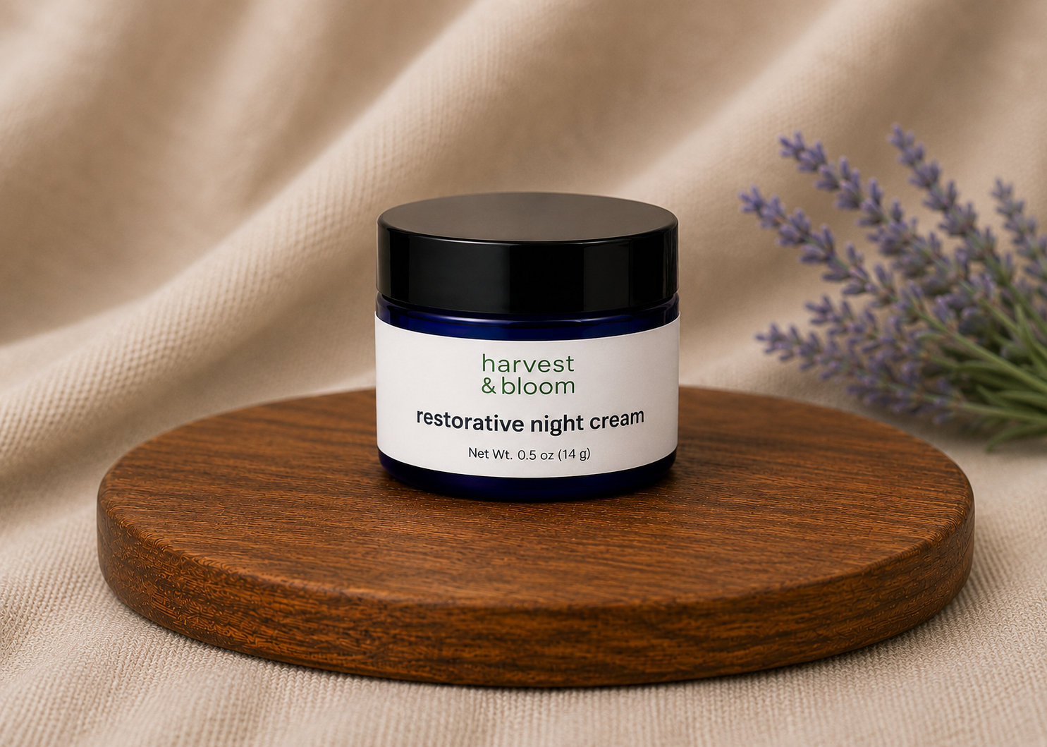 Harvest and Bloom restorative night cream in a premium blue glass jar with a black lid against a dark, calming fabric backdrop.