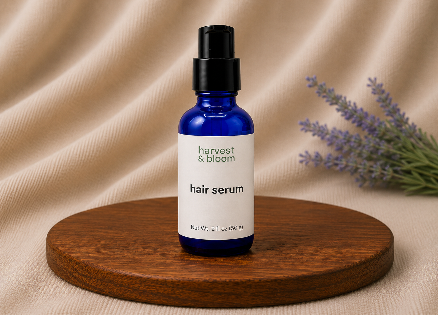 Harvest and Bloom natural hair serum in a blue glass bottle with a black treatment pump dispenser against a soft fabric backdrop.