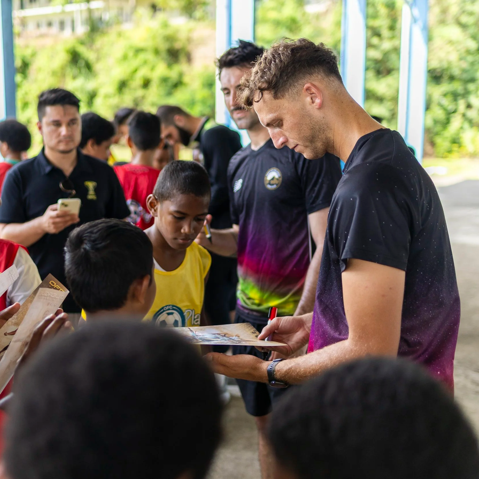 A group of children being visited by professional football players from the South Island of NZ. Signing autographs after a fun session.