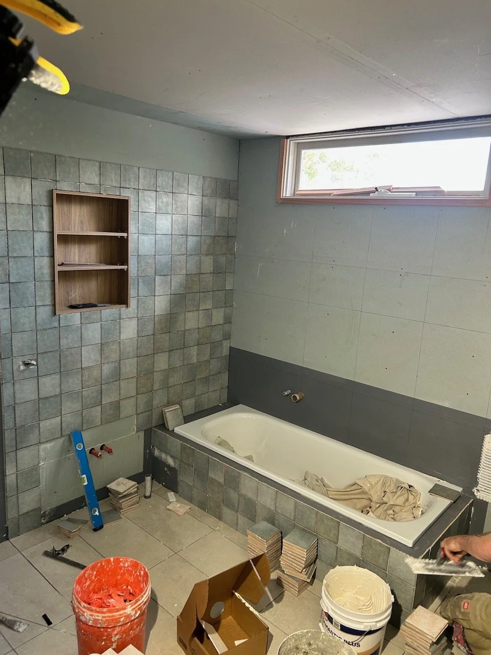 Bathroom under renovation with tiled walls, built-in bathtub.