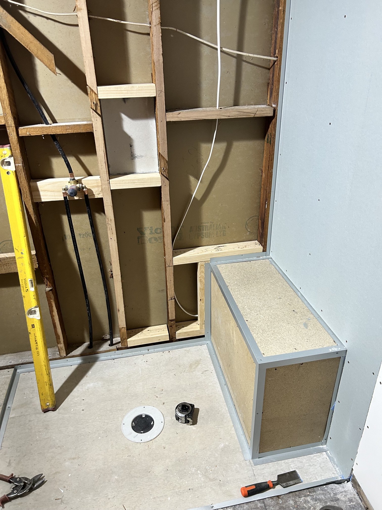 Bathroom renovation showing exposed wall studs, plumbing, electrical wiring, drywall.