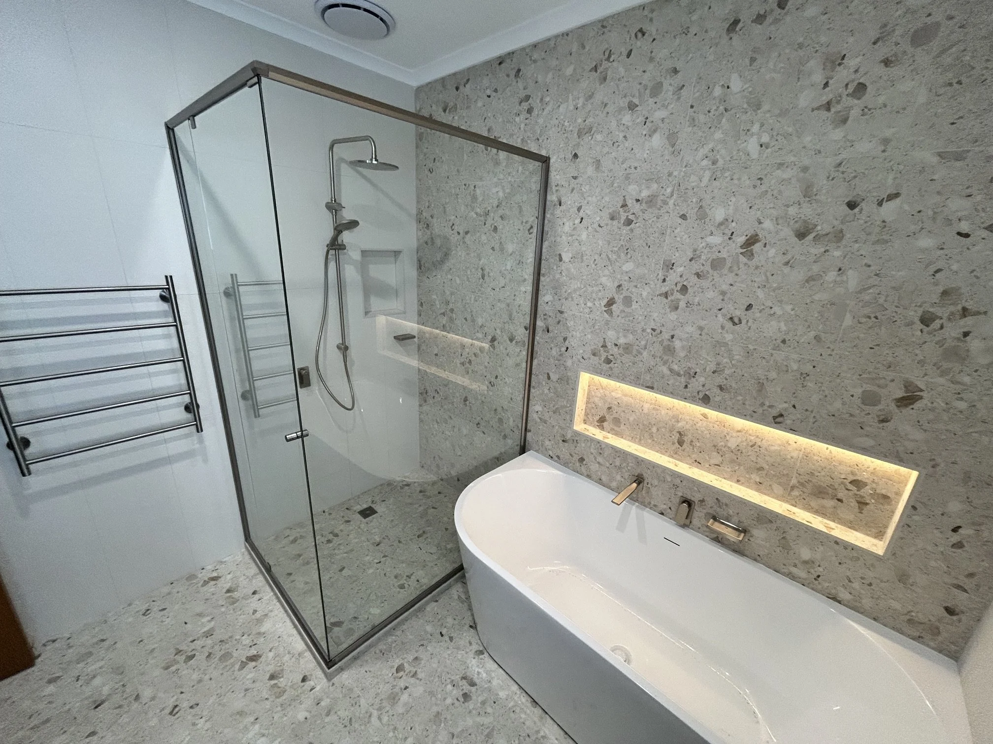Modern bathroom with a freestanding bathtub, a walk-in shower with a glass enclosure, and marble tile flooring and walls.