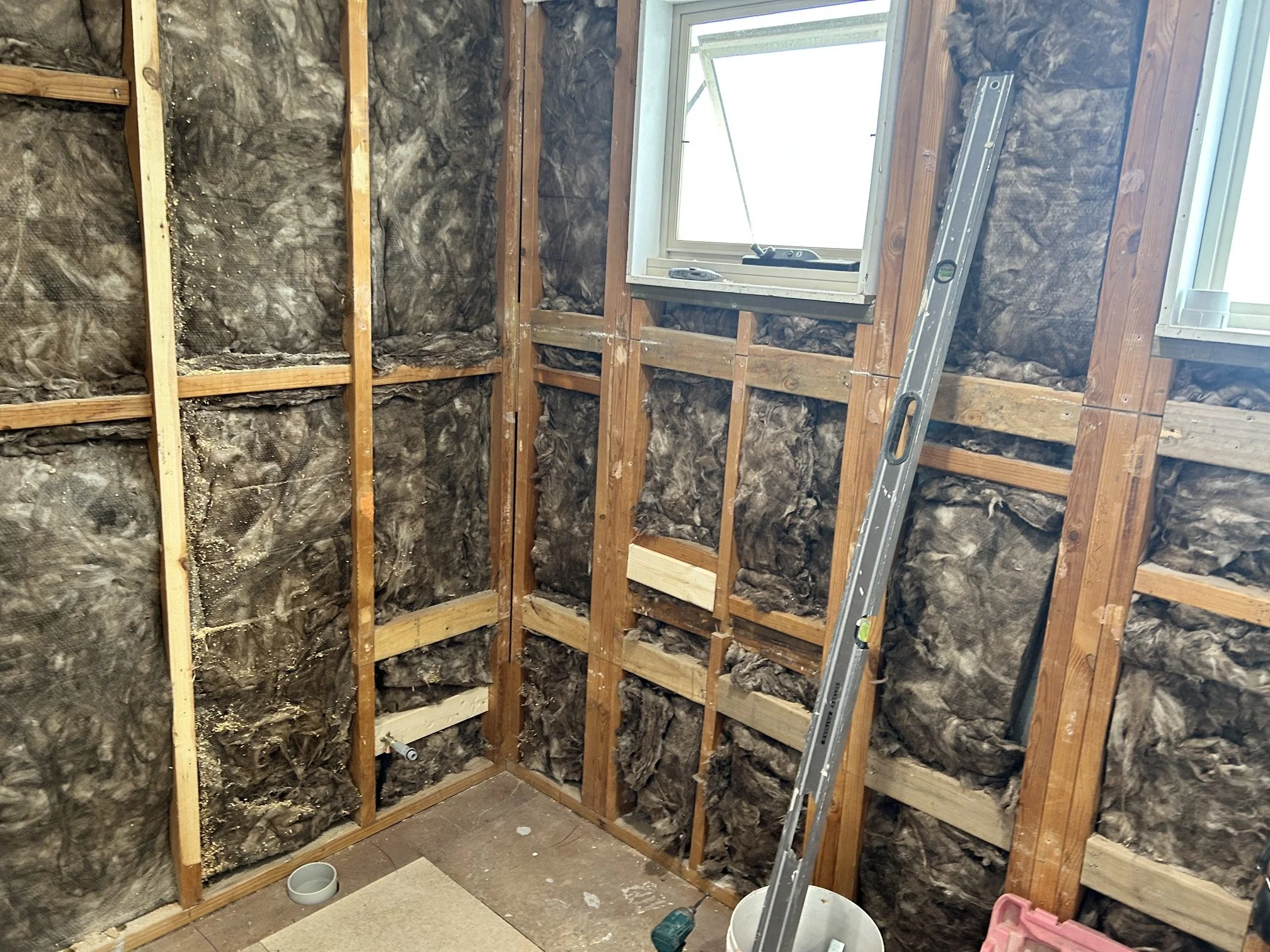 Unfinished room with exposed wood framing, fiberglass insulation.