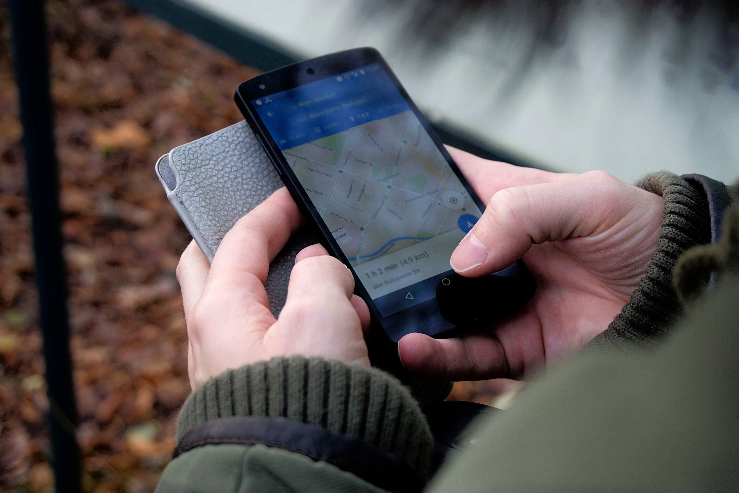 A person holds a phone displaying a Google Maps navigation route outdoors.