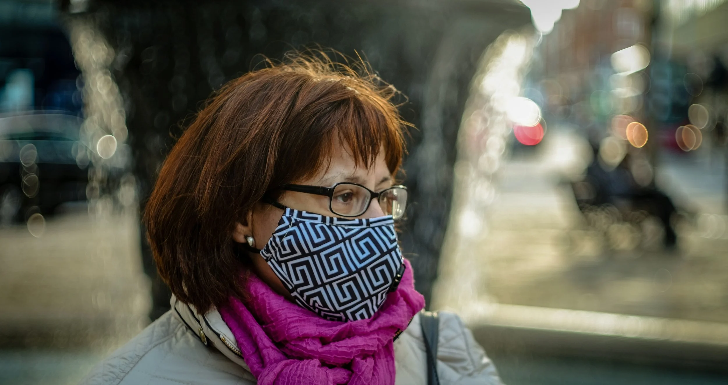 A woman in a face mask walks through a city.